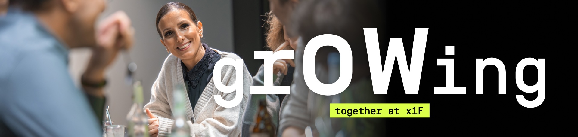 Grafik mit dem großen Schriftzug „grOWing“ auf schwarzem Hintergrund und dem Zusatz „together at x1F“ in einem neongelben Balken. Links im Bild sitzen mehrere Personen an einem Tisch und unterhalten sich in einer Besprechungssituation.